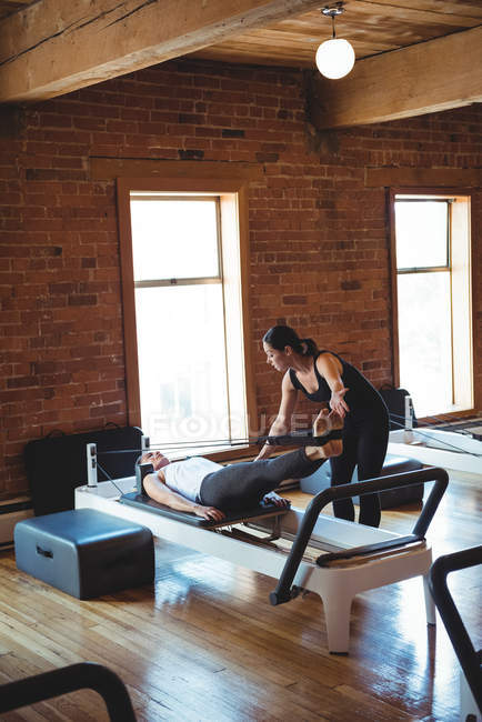 Treinador ajudando mulher enquanto pratica pilates no estúdio de fitness — Fotografia de Stock