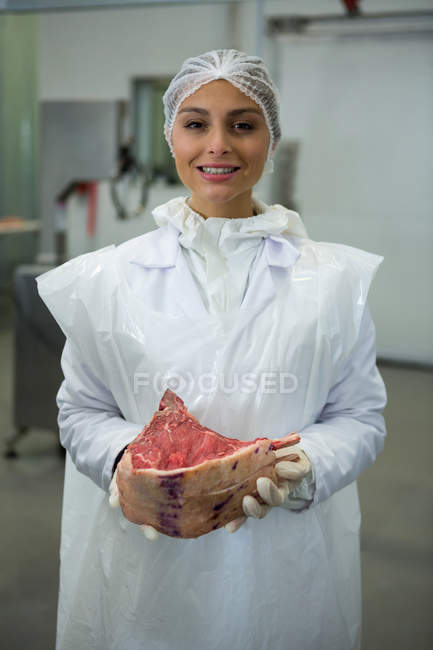 Portrait of female butcher holding meat — Stock Photo
