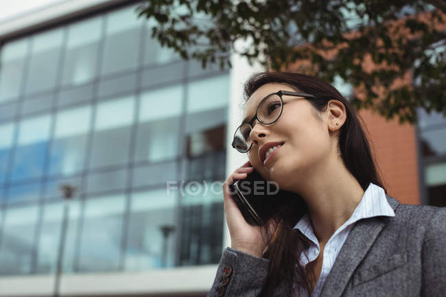 Businesswoman talking on mobile phone while standing at city street — Stock Photo