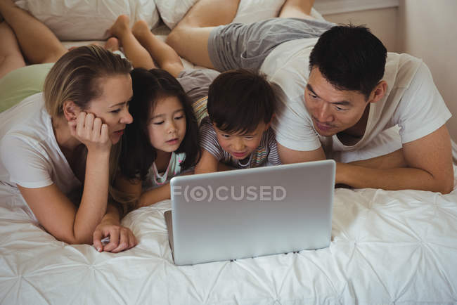 Счастливая семья использует ноутбук в спальне дома — стоковое фото