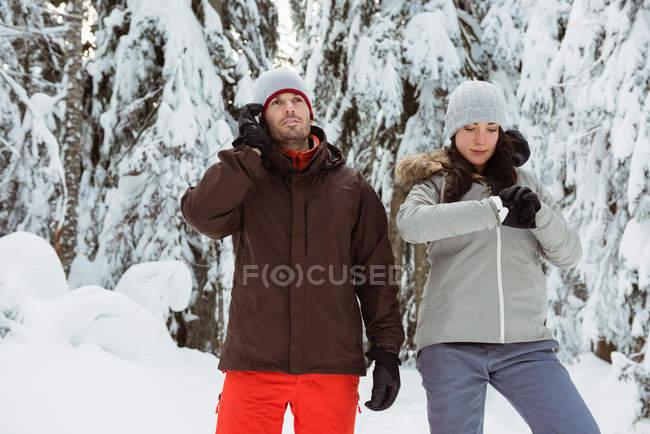 Hombre hablando por teléfono móvil y mujer comprobando el tiempo en la montaña cubierta de nieve - foto de stock