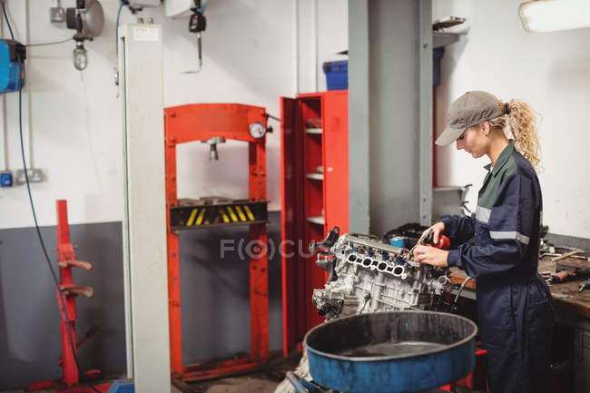 Feminino mecânico óleo peças de carro na garagem de reparação — Fotografia de Stock