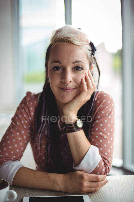 Retrato de mujer sonriente con tableta digital en la mesa en la cafetería - foto de stock