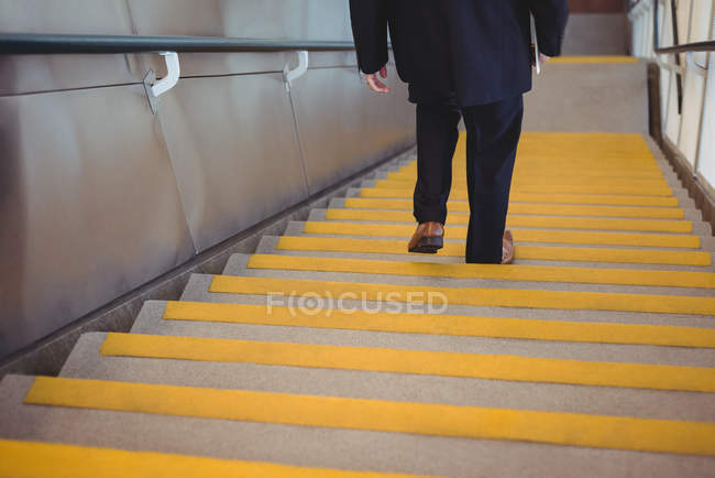 Uomo d'affari con un diario che scende le scale in ufficio — Foto stock