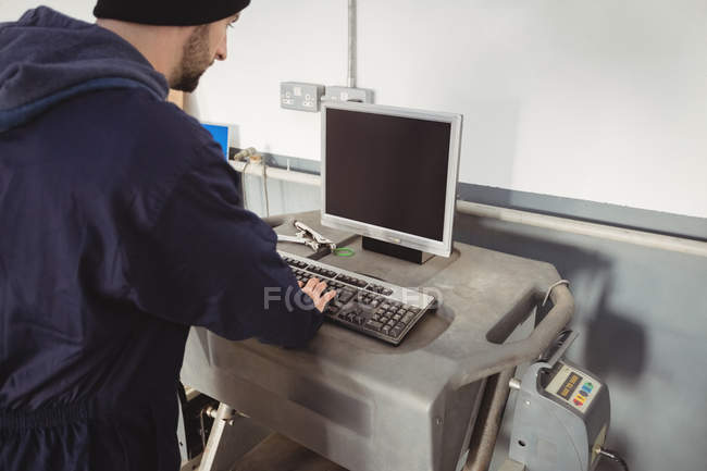 Механік, що працює на персональному комп'ютері в ремонті гаража — стокове фото