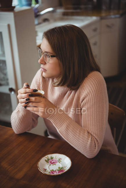 Femme ayant une tasse de café dans le salon à la maison — Photo de stock