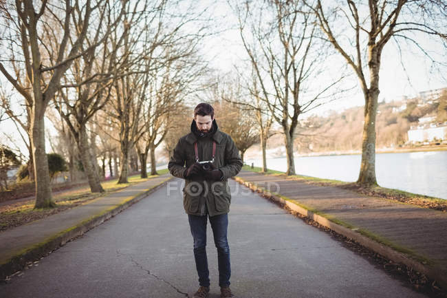 Homem olhando para exibição na câmera perto da ribeira — Fotografia de Stock