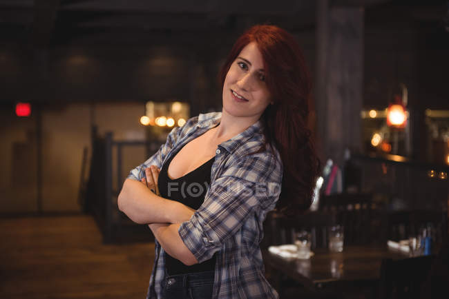 Retrato de uma bela mulher sorrindo com os braços dobrados no bar — Fotografia de Stock