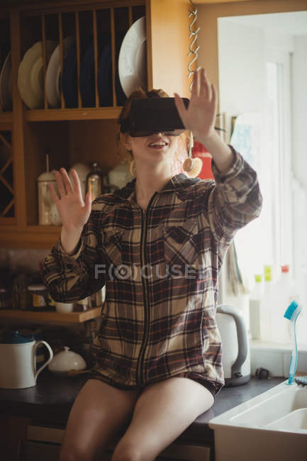 Mulher experimentando fone de ouvido realidade virtual na cozinha em casa — Fotografia de Stock