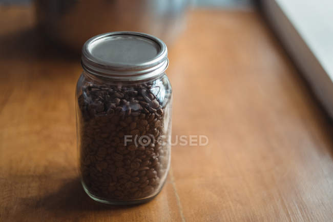 Primer plano de un frasco de granos de café tostados - foto de stock