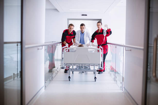 Médicos empurrando cama de maca de emergência no corredor do hospital — Fotografia de Stock