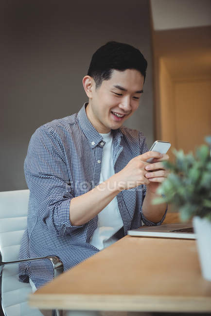 Executivo de negócios sorrindo usando telefone celular no escritório — Fotografia de Stock