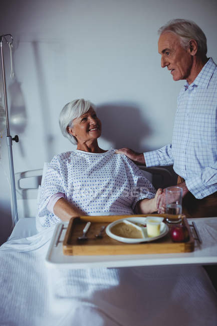 Senior woman interacting with senior man in the ward at hospital — Stock Photo