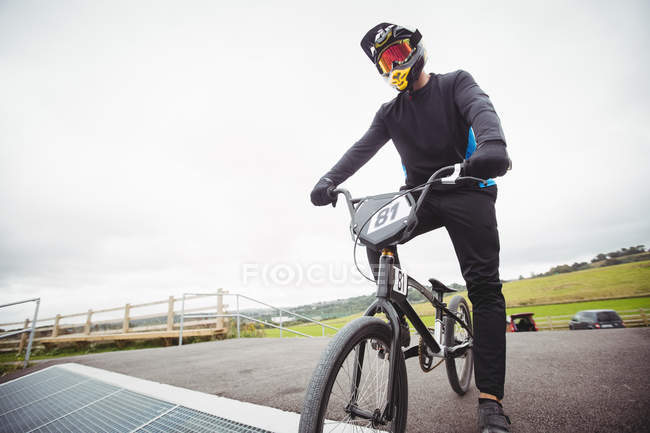Велогонщик готовится к гонкам BMX на старте пандуса в скейтпарке — стоковое фото