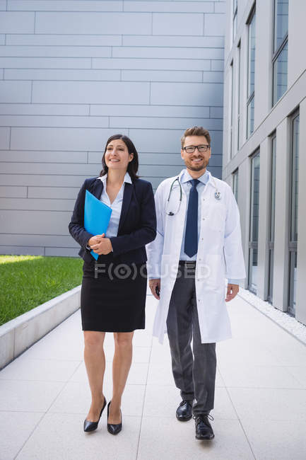 Médicos sonrientes caminando juntos en los locales del hospital - foto de stock