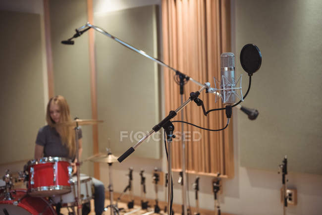 Microfono in studio di registrazione con musicista femminile in background — Foto stock