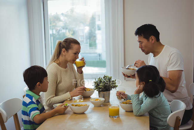 Família feliz tendo refeição na mesa de jantar em casa — Fotografia de Stock