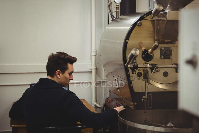 Homem sentado ao lado da máquina de torrefação de café no café — Fotografia de Stock
