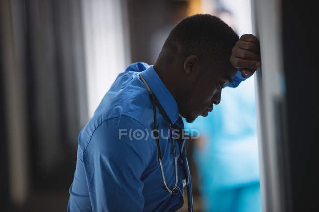 Médico triste inclinado na parede no corredor do hospital — Fotografia de Stock