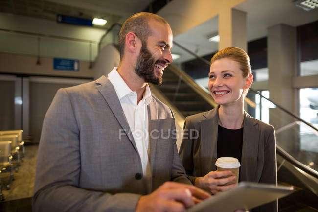 Деловые люди обсуждают за цифровым планшетом в аэропорту — стоковое фото