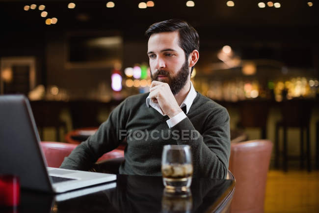 Человек смотрит на ноутбук в интерьере бара — стоковое фото