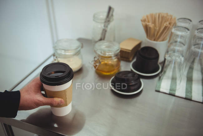 Mão mantendo uma xícara de café na mesa de aço no café — Fotografia de Stock