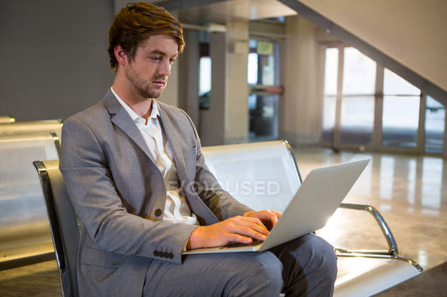 Empresário trabalhando em seu laptop na área de espera no terminal do aeroporto — Fotografia de Stock