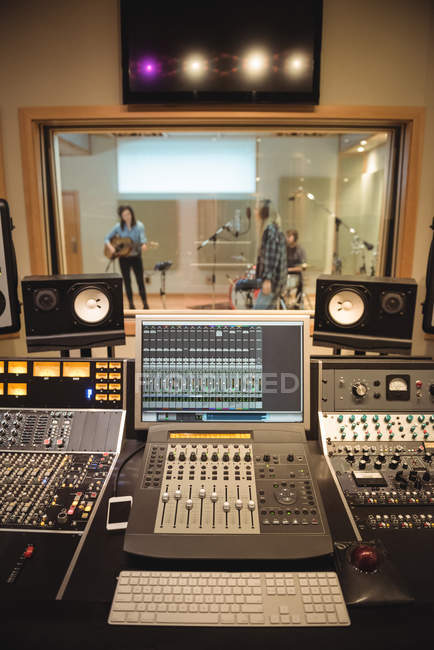 Звукорежиссер в студии звукозаписи с музыкантами на заднем плане — стоковое фото