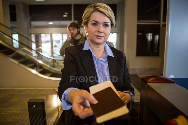 Businesswoman handing over boarding pass at counter in airport terminal — Stock Photo
