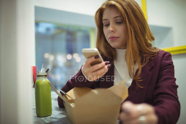 Mujer tomando fotos de ensalada en el teléfono móvil en el restaurante - foto de stock