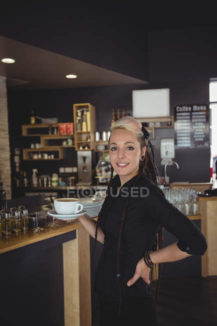 Portrait de serveuse debout avec une tasse de café dans un café — Photo de stock