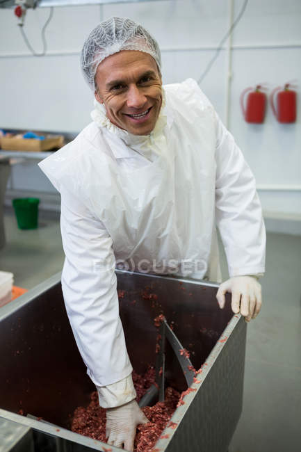 Retrato de açougueiro removendo carne picada da máquina na fábrica de carne — Fotografia de Stock