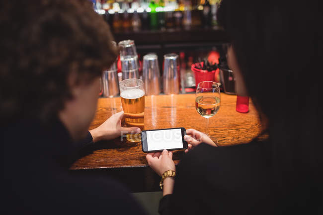 Couple using mobile phone at bar counter — Stock Photo