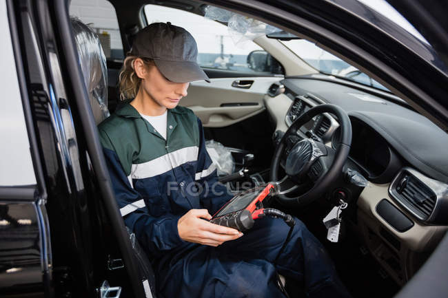 Female mechanic using electronic diagnostic device in repair garage — Stock Photo
