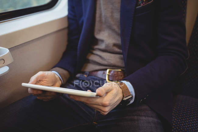 Parte média do empresário segurando tablet digital enquanto viaja em trem — Fotografia de Stock