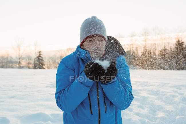Homem soprando neve e desfrutando no dia ensolarado de inverno — Fotografia de Stock