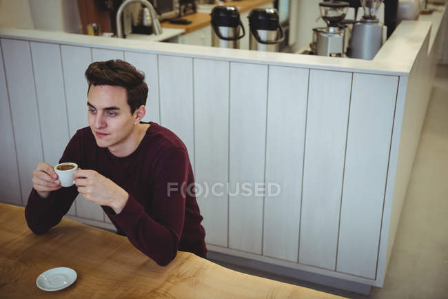 Homem tomando café enquanto sentado em uma cafeteria — Fotografia de Stock