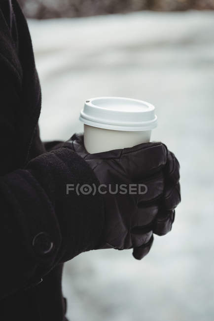 Hands of man in warm clothing holding coffee cup during winter — Stock Photo