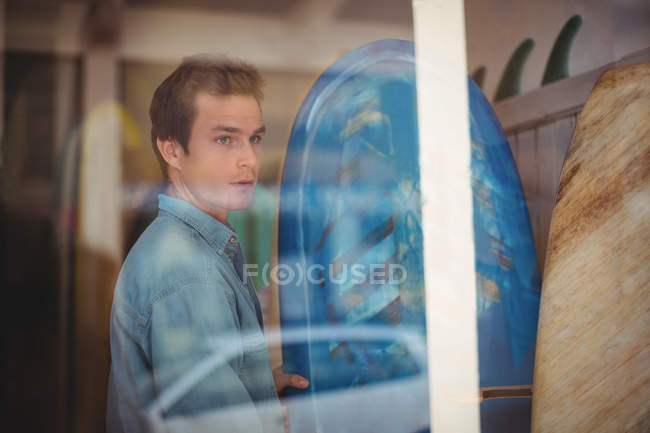 Hombre seleccionando tabla de surf azul en una tienda - foto de stock