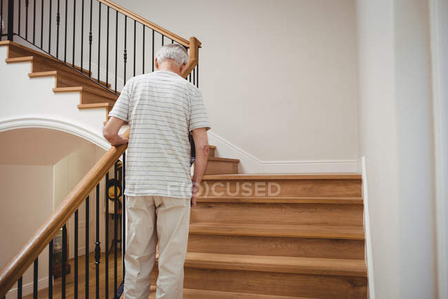 Un aîné monte les escaliers à la maison — Photo de stock