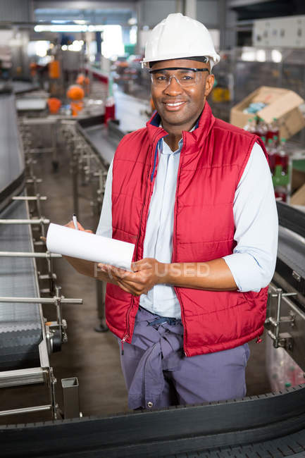 Porträt eines lächelnden männlichen Mitarbeiters, der über Produkte in einer Saftfabrik schreibt — Stockfoto