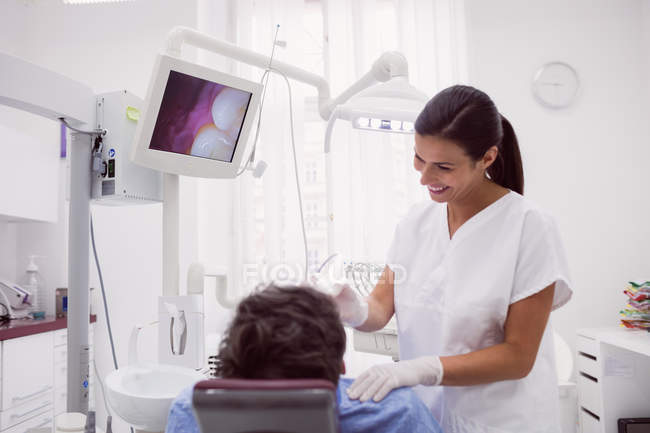 Une dentiste examine une patiente en clinique dentaire — Photo de stock