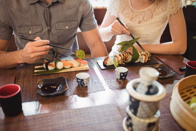 Partie médiane du couple ayant des sushis au restaurant — Photo de stock