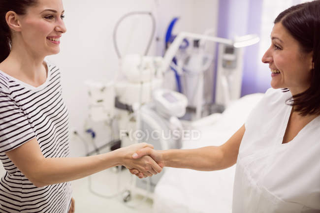 Doctor estrechando la mano con el paciente en la clínica - foto de stock