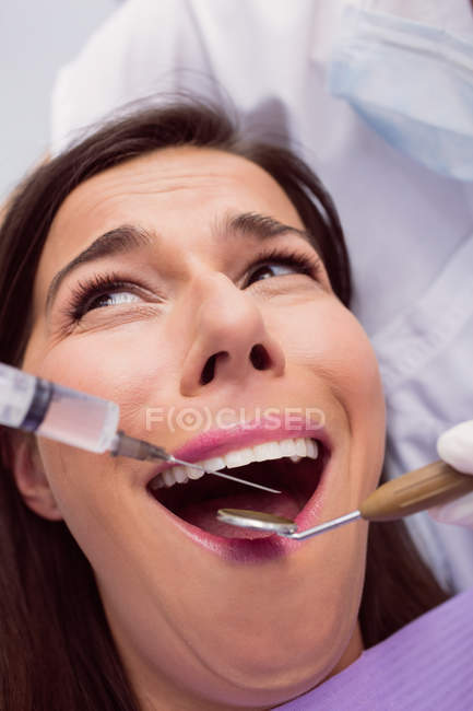 Dentista inyectando anestésicos en la boca del paciente asustado en la clínica - foto de stock