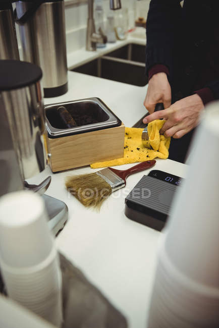 Мужчина чистит портативный фильтр тканью в кофейне — стоковое фото