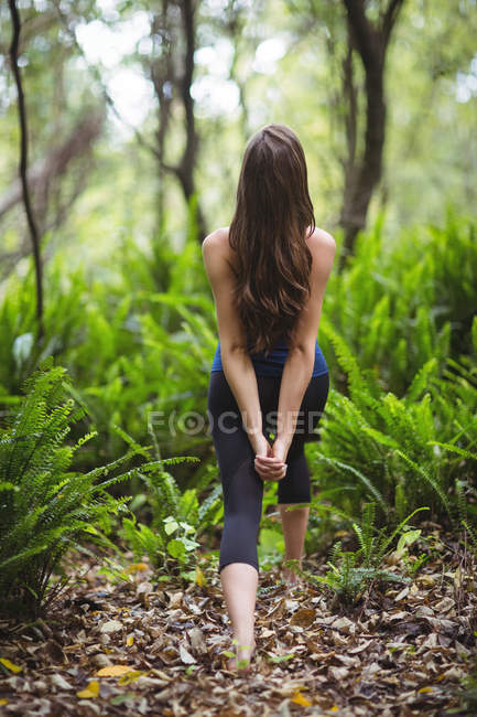 Вид ззаду жінки, що виконує йогу в лісі — стокове фото
