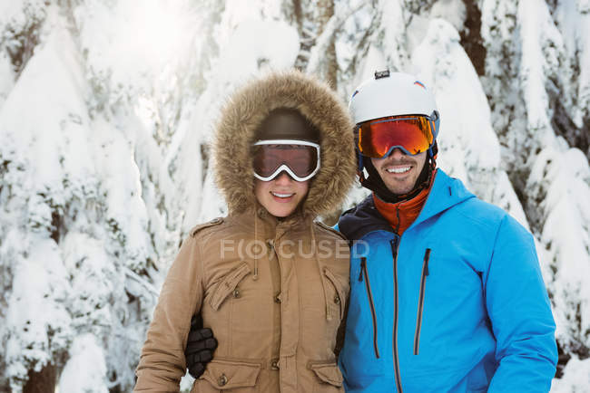 Feliz pareja de esquiadores de pie en el paisaje cubierto de nieve - foto de stock