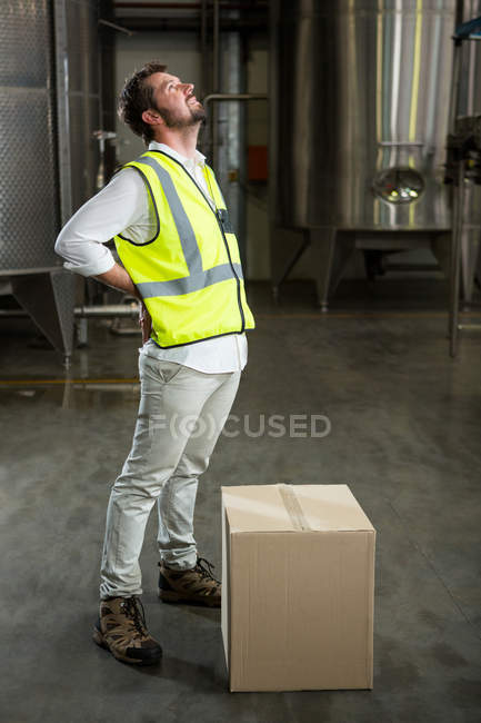 Comprimento total do trabalhador masculino cansado em pé no armazém — Fotografia de Stock