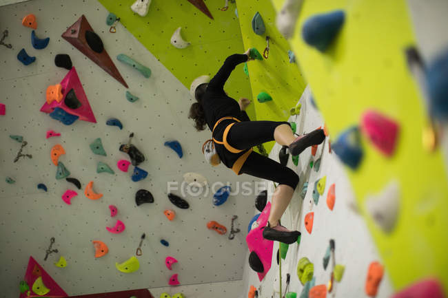 Жінка практикує скелелазіння на штучній стіні скелелазіння в спортзалі — стокове фото